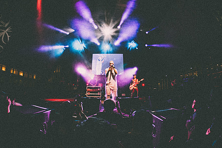 man singing in front of audiences under stage lights thumbnail