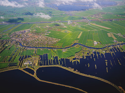 aerial photography of green field near calm water thumbnail