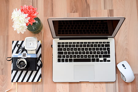 silver MacBook beside white wireless computer mouse on brown wooden surface thumbnail