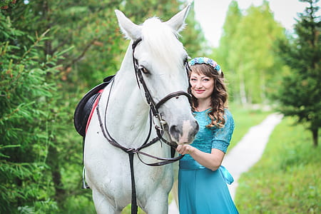 woman touching white horse surrounded by trees thumbnail