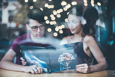 man and woman reading Luminescence book with bokeh lights on background thumbnail