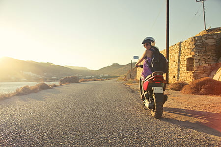 Woman Riding Motor Scooter Travelling on Asphalt Road during Sunrise thumbnail