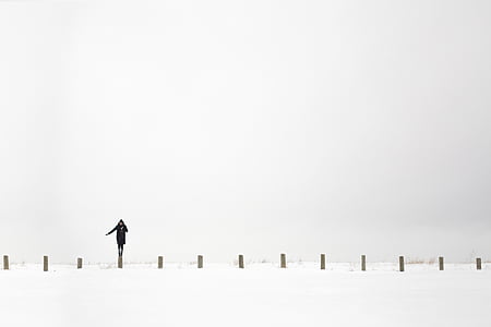 person standing on wooden fence post near snow covered ground thumbnail