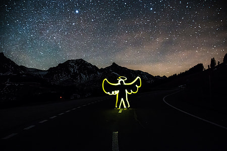 angel neon light on road under starry sky thumbnail