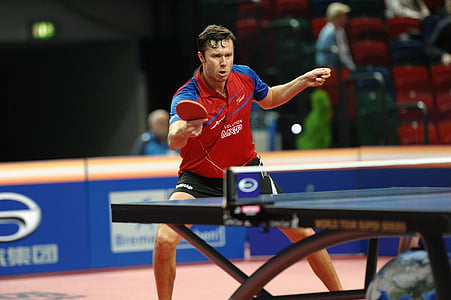 man in red and blue polo shirt playing table tennis thumbnail