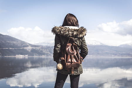 man in jacket standing near body of water thumbnail