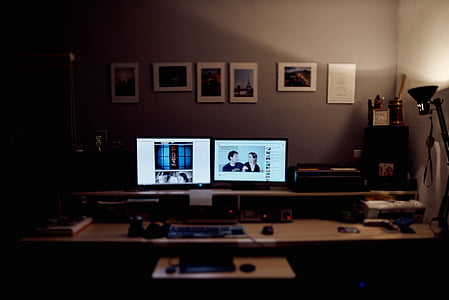 two turned on flat screen monitors on white desk thumbnail