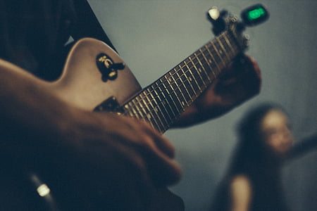 selective focus photography of person playing guitar thumbnail