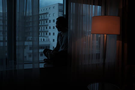 man sitting beside glass window and floor lamp thumbnail