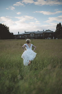 woman wearing white lace cap-sleeved dress running on green grass field thumbnail