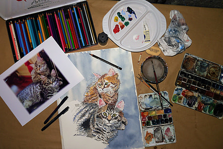 two orange brown tabby cats photo and painting on brown wooden table with color pencils and paint palettes thumbnail
