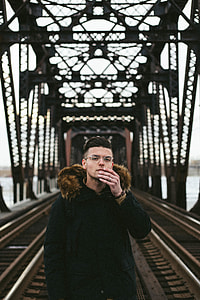 man wearing black fleece coat standing on concrete bridge during daytime thumbnail