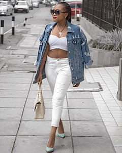 Photo of Woman Wearing White Crop Top and Denim Jacket Walking in Pavement Holding Bag thumbnail