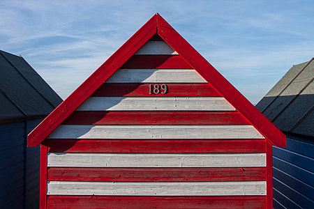 A red and white-striped beach hut sits on the Kent Coast in Southern England thumbnail