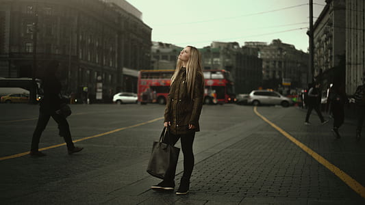 woman wearing green jacket and black pants holding black leather bag thumbnail