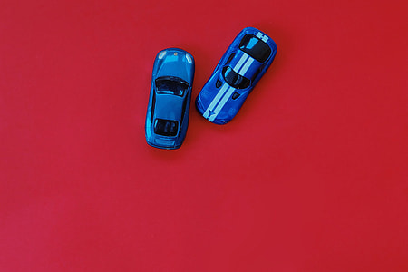 two blue die cast toy cars on red wooden table top thumbnail