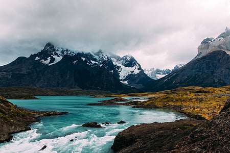 body of water with snow-capped mountain at distance thumbnail