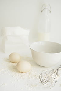 two white eggs beside white ceramic bowl on white surface thumbnail