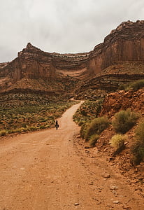 person walking near mountain under cloudy sky thumbnail