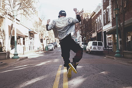 man wearing white jacket and black pants about to jump on street during daytime thumbnail