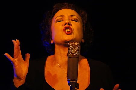 woman wearing black scoop-neck top singing in front of condenser microphone thumbnail