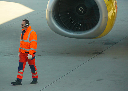 man with white headset walking in front of airplane during daytime thumbnail