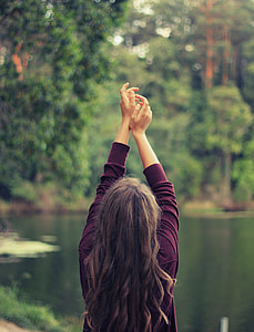 woman raising her hands on the sky while standing infront of lake thumbnail