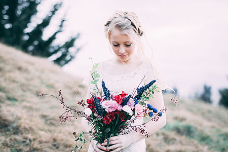 woman in white long-sleeved top holding flowers thumbnail