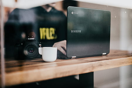 person in front of laptop beside DSLR camera on table thumbnail