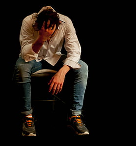 man wearing white dress shirt and blue denim jeans while sitting thumbnail