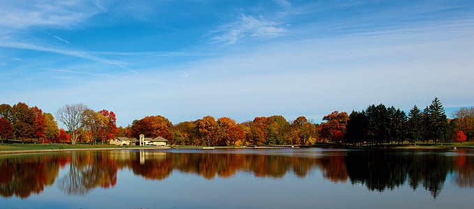 grey estate seen across glassy lake under white and blue sky thumbnail