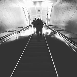 grayscale photo of people climbing using escalator stairs thumbnail