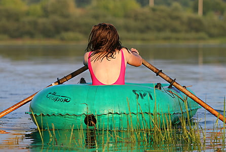 woman wearing red swimwear sitting and paddling in green inflatable boat over body of water thumbnail