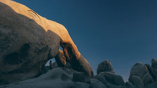person standing on rock formation under clear sky thumbnail