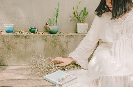 Woman Holding Dried Flowers Beside Book While Sitting thumbnail