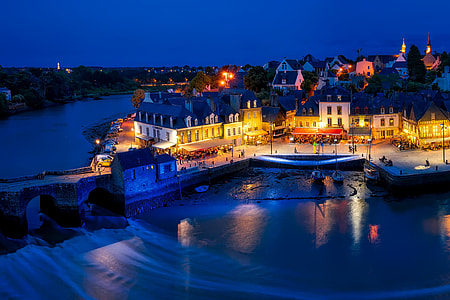 concrete buildings with lights turned on near body of water under blue sky during night thumbnail