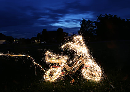 bike decorated with string lights parkin on garden during nighttime thumbnail