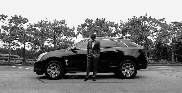 man standing beside black SUV during daytime thumbnail