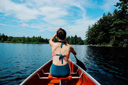 woman wearing teal and red bikini set while using a boat paddle thumbnail