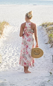 woman standing in the sand holding her hat thumbnail