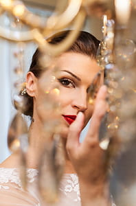 woman wearing white floral illusion-neckline shirt holding crystal thumbnail