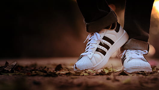 person in black jeans wearing pair of white-and-black adidas sneakers thumbnail