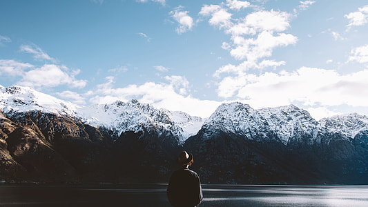 person facing mountain covered with snow under cloudy sky thumbnail