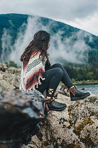 woman sitting on boulder near body of water thumbnail
