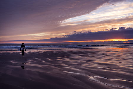 person holding surfboard near body of water thumbnail
