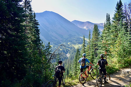 three men riding bike besides mountain cliff during daytime thumbnail