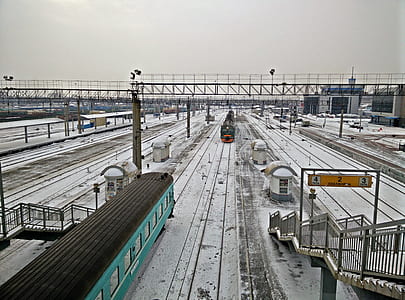 two gray and green trains on road covered with snow at daytime thumbnail