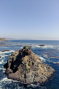 gray rocky mountain in sea under blue sky at daytime thumbnail