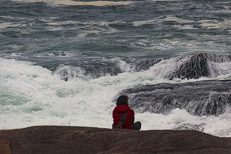 woman wearing red hoodie sitting near sea shore thumbnail