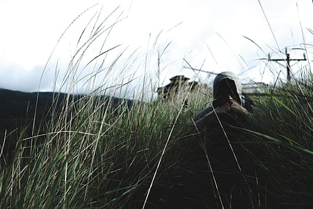person with gray hoodie top sitting on green grass field at daytime thumbnail